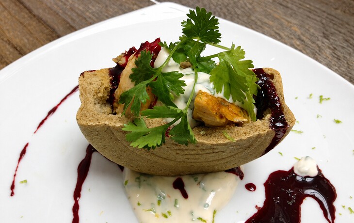 Vorspeise in einer Brotschale mit Geflügel, Kräutern und dunkler Sauce